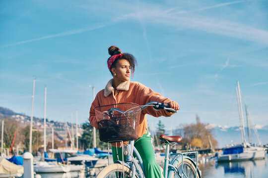 Outdoor fashion portrait of pretty african woman walking with bicycle
