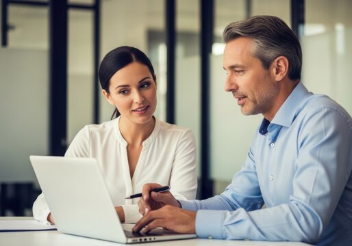 Two professionals collaborating on a laptop in an office setting