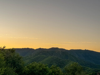 Sunset Over Mountain Ridge with Distant City Skyline