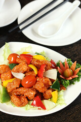 Delicious sweet and sour pork, featuring crispy fried pork pieces tossed with vibrant bell peppers, onions, and cherry tomatoes