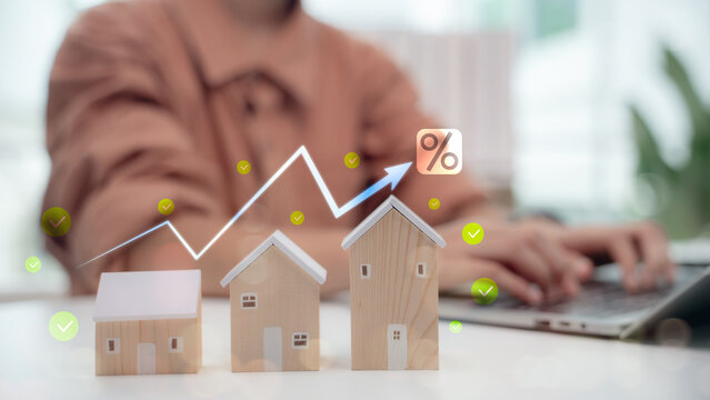 Rising housing market concept with wooden house models and increasing graph, symbolizing mortgage interest rates, real estate investment growth, and property price trends.