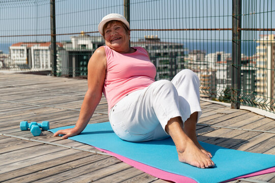 Senior woman smiling during outdoor exercise on a rooftop