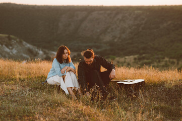 A couple connects in natures beauty, creating music and lasting memories at sunset amid scenic hills