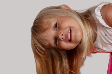 happy blond blue-eyed girl 4 years old looking curious and smiling