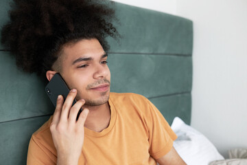 Indoor closeup of z-generation guy with afro hair talking on phone with his girlfriend, wishing...