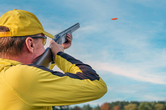 A shooter in a yellow uniform takes a lead before shooting at a clay pigeon
