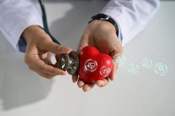 Doctor holding a red heart model with stethoscope, representing cardiology and heart checkup