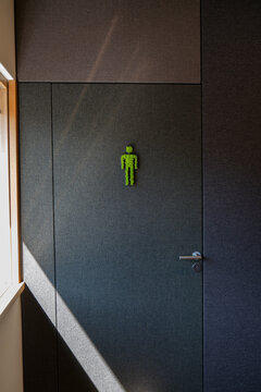 Green restroom symbol on business bathroom door in modern interior
