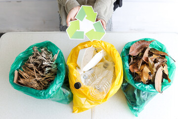 Person Hands Holding Recycle Symbol With Sorted Waste Paper, Plastic And Leaves For Recycling