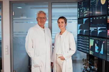 Doctor and colleague in clinic analyzing medical data on large monitors