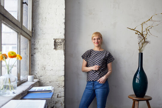 Portrait of woman standing in bright urban loft with industrial charm