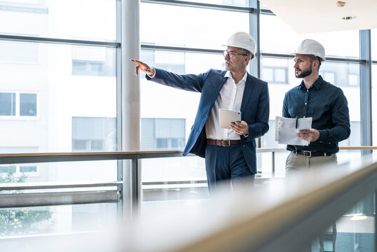 Architects in safety helmets consulting on a project in modern office