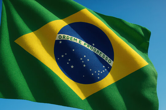Brazilian flag waving against clear blue sky with bright colors and symbols. Brazil Independence Day
