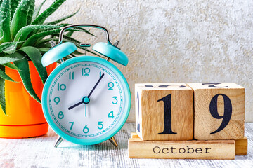 Wooden calendar with the date October 19.Monthly calendar for planning and management concept with alarm clock on wooden background