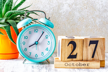 Wooden calendar with the date October 27.Monthly calendar for planning and management concept with alarm clock on wooden background