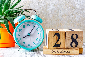 Wooden calendar with the date October 28.Monthly calendar for planning and management concept with alarm clock on wooden background