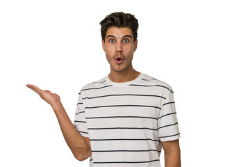 Young handsome caucasian man isolated on white background impressed holding copy space on palm.