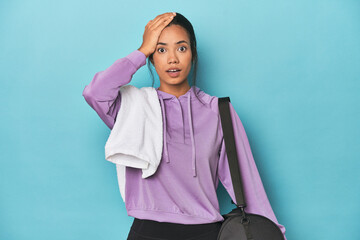 Filipina with gym gear on blue studio being shocked, she has remembered important meeting.