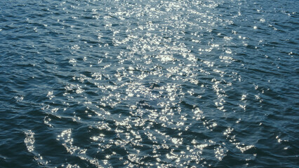Sparkling sunlight shimmering on ocean waves. Natural sea ripple surface background for environmental concepts.