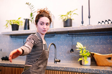 Woman cooking in modern London kitchen with apron and plants