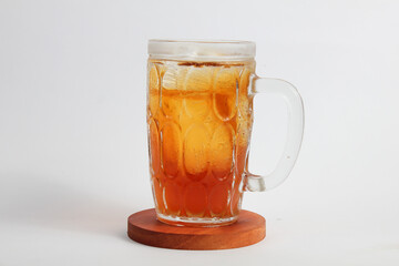 A glass of fresh sweet tea on a round wooden board isolated on a white background