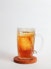 A glass of fresh sweet tea on a round wooden board isolated on a white background