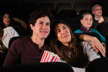 Happy couple enjoying a movie at the cinema, eating popcorn and sharing a special moment together