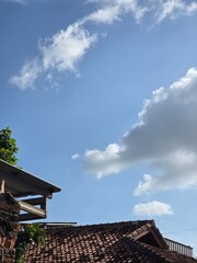 Sunny weather, blue sky with white clouds, tiled roofs and green trees