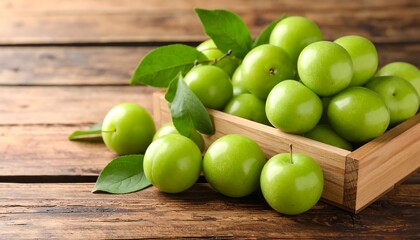 Wooden crate overflowing with vibrant green plums and leaves, set against a rustic wood backdrop