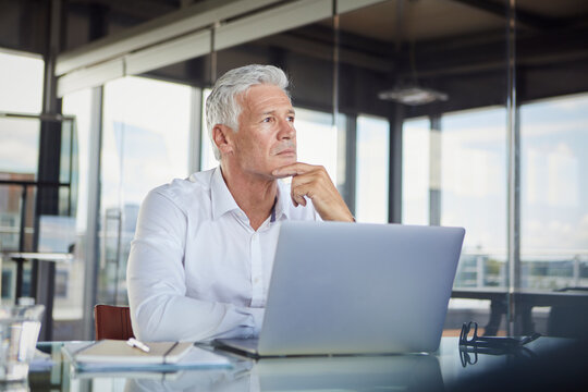 Businessman in office thinking with expression of stress and success