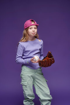 Sporty girl with baseball glove and ball in studio portrait