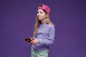 Child in streetwear with cap playing video game indoors