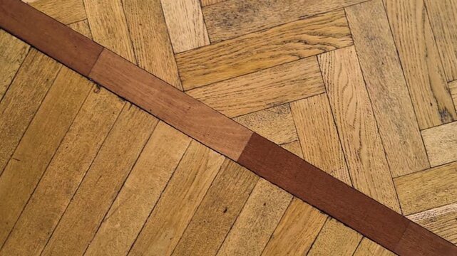 Diagonal parquet flooring with dark brown wood inlay. Dolly move, top view.