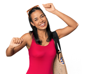 Young Filipina with beach bag celebrating a special day, jumps and raise arms with energy.