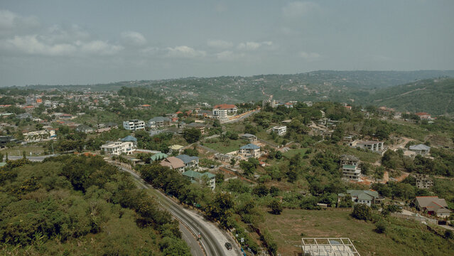 Aerial view of winding roads cutting through the verdant hillsides dotted with homes, a blend of nature and architecture, Aburi, Eastern Region, Ghana.