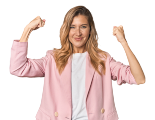Young blonde in stylish pink suit showing strength gesture with arms, symbol of feminine power