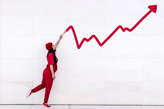 Businesswoman in red pointing at upward graph showing financial growth