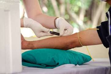 Close up nurse pricking needle syringe in the arm patient drawing blood sample for blood test ,...