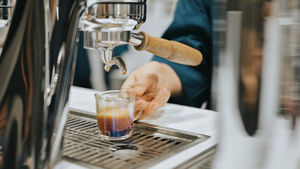 Close-up of espresso pouring fresh black coffee from coffee machine. Coffee extraction from a professional coffee machine with a bottomless filter. Professional coffee brewing.