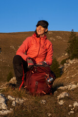 A female hiker unpacks her gear and relaxes after a challenging day of mountain trekking, enjoying the tranquility of a sunset