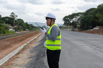 A engineer   on a vast road construction site. Traffic cones and barriers are, signifying   area ...
