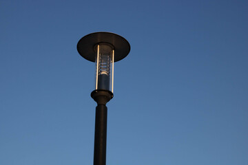 A beautiful iron streetlight with a round lid against a clear blue sky. A minimalist composition...