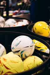 Football balls in basket for sale at sports store, close-up view.