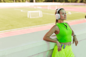 Portrait of a young Caucasian female with an athletic figure listening to music on headphones	
