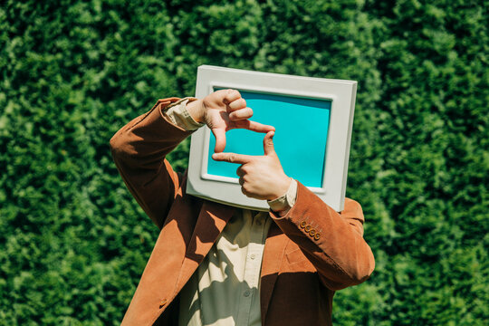 Person with retro monitor head framing face outdoors as visual metaphor