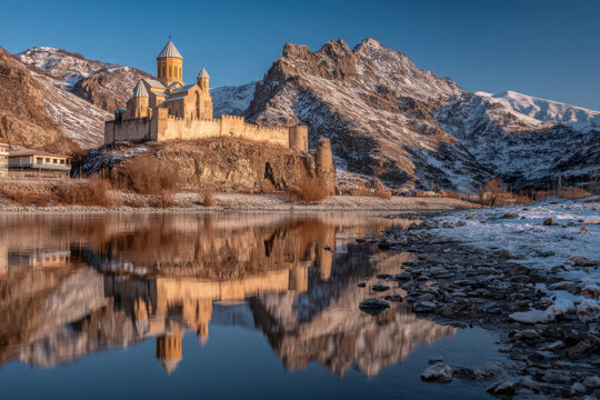 Ananuri fortress reflected in calm zhinvali reservoir with surrounding green mountains