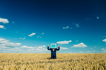 Businesswoman with retro computer monitor in wheat field under blue sky