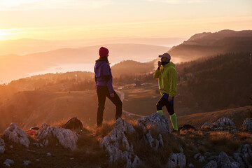 A joyful couple celebrates their victorious ascent to the mountain summit, embracing each other...