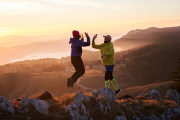 A joyful couple celebrates their victorious ascent to the mountain summit, embracing each other...