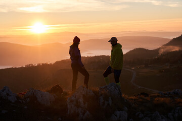 A joyful couple celebrates their victorious ascent to the mountain summit, embracing each other...
